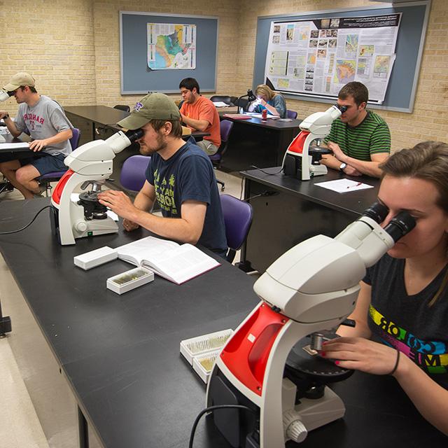 地质 students study samples under microscopes